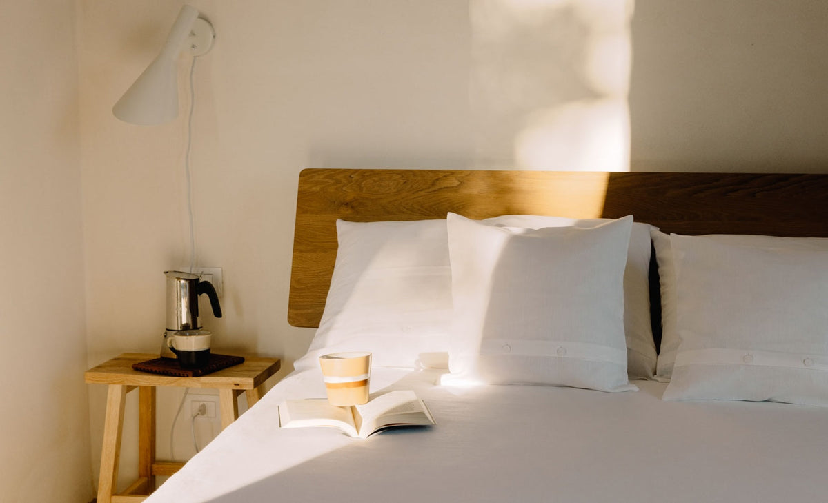 Ein Bett mit weißer Leinenbettwäsche.