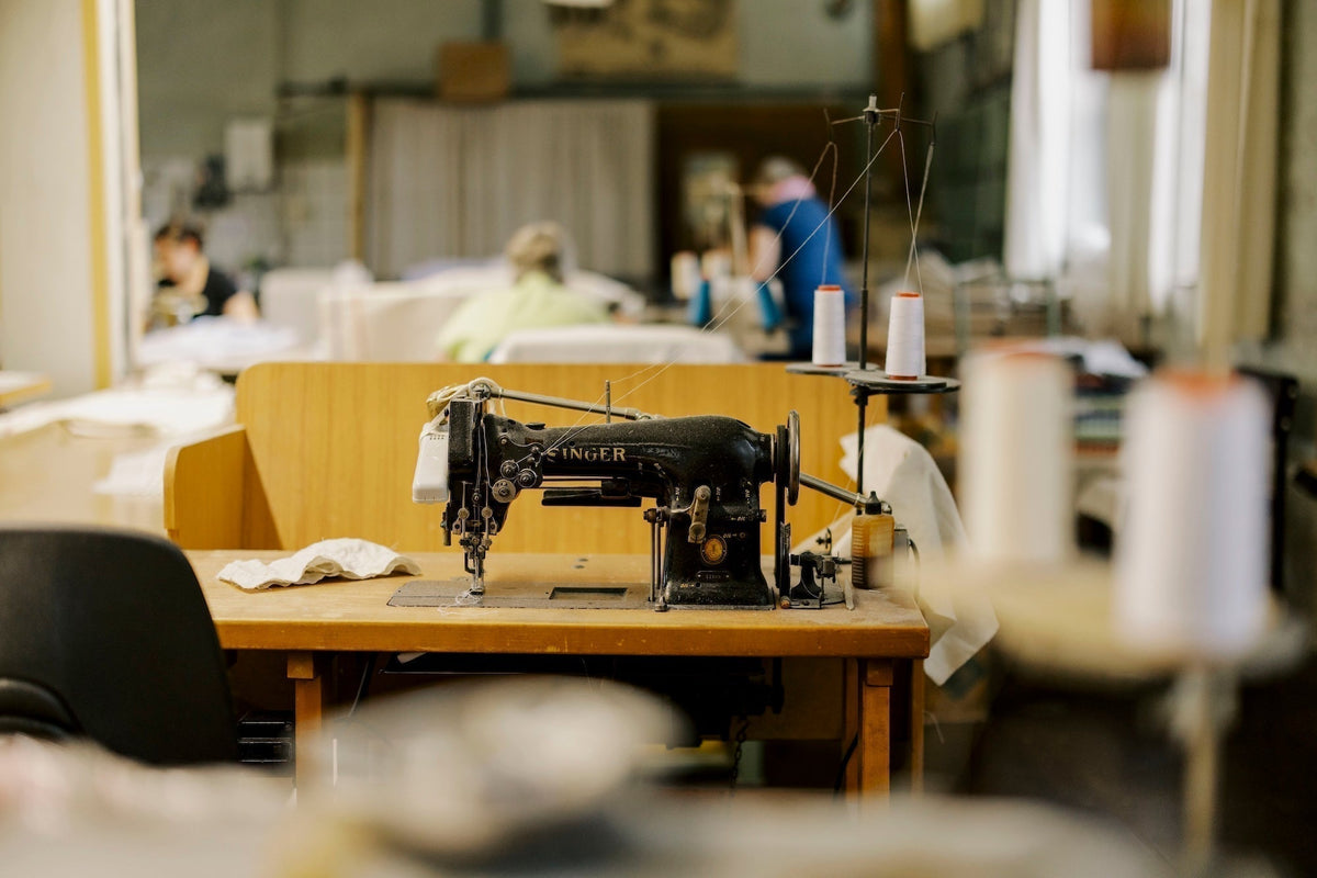 Konfektionsabteilung in einer Leinenweberei mit Nähmaschine im Fokus, Hintergrund ist verschwommen.