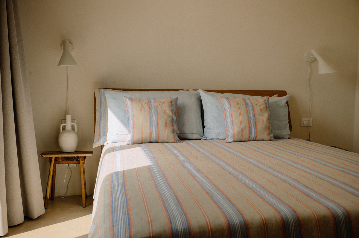 Doppelbett mit Leinenbettwäsche mit Blockstreifen in Schlafzimmer.