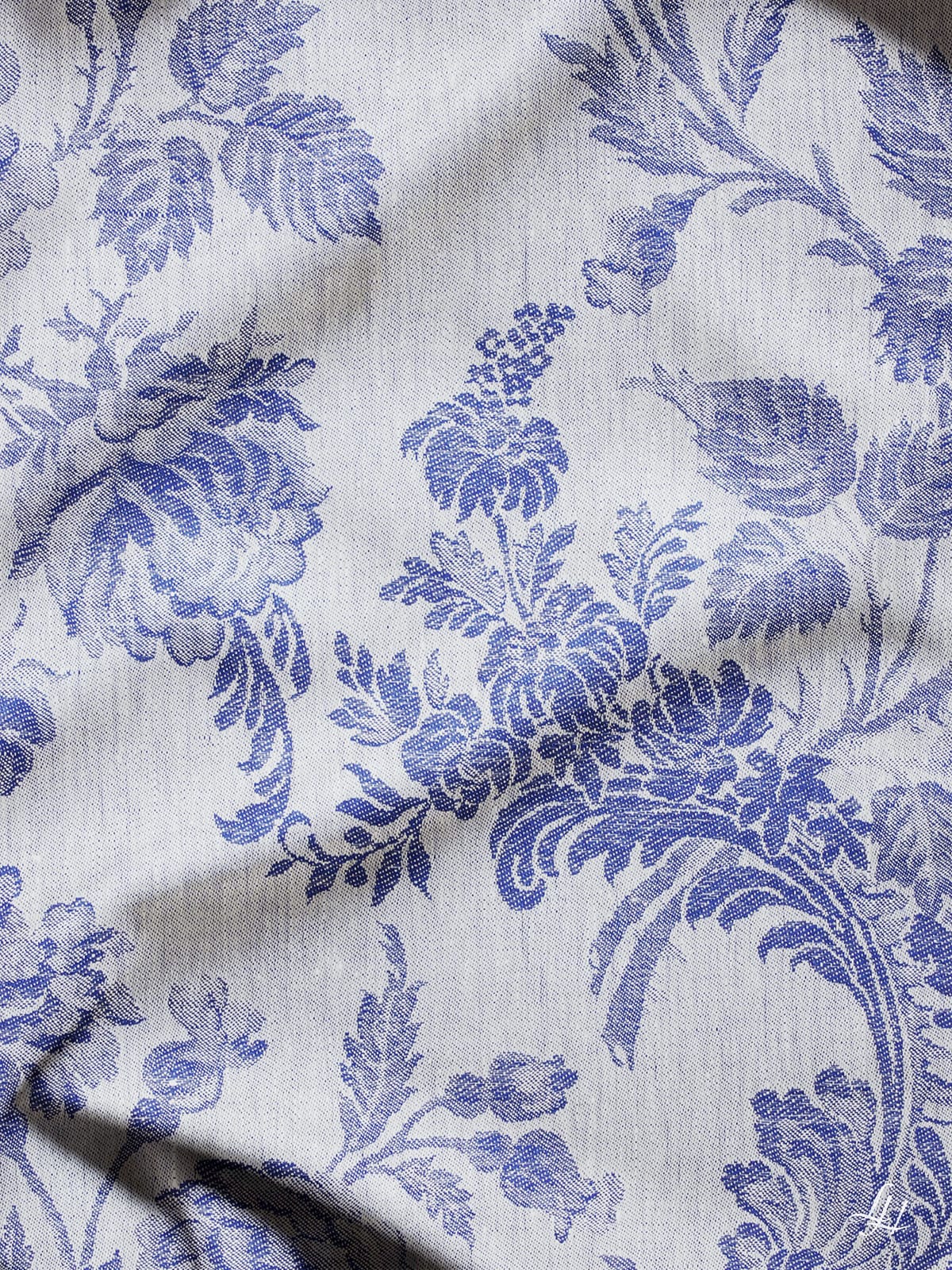 Nahaufnahme eines europäischen Leinenstoffs in Chrysantheme Blau (Hell) mit einem komplizierten blauen Blumenmuster und leichten Falten.
